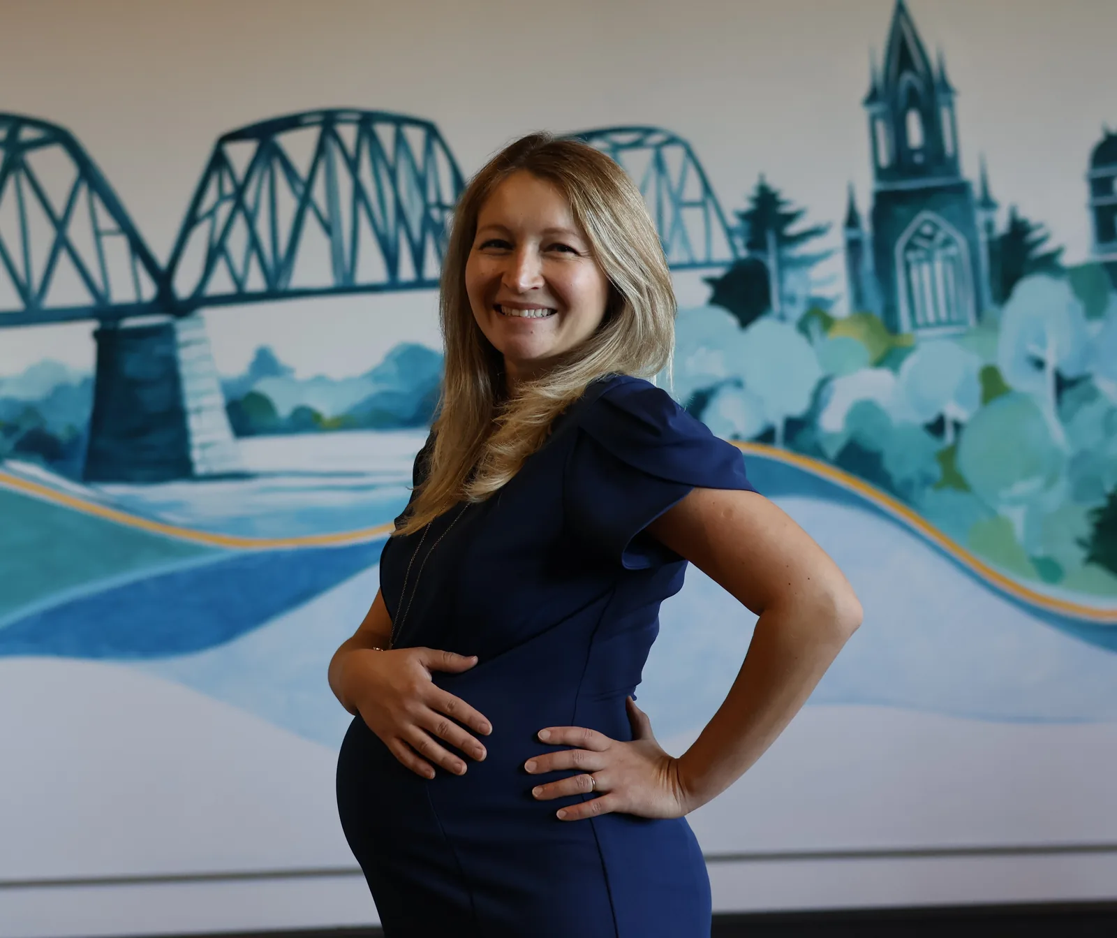 Corina, co-founder of Tidal Signal, smiling in front of the studio mural