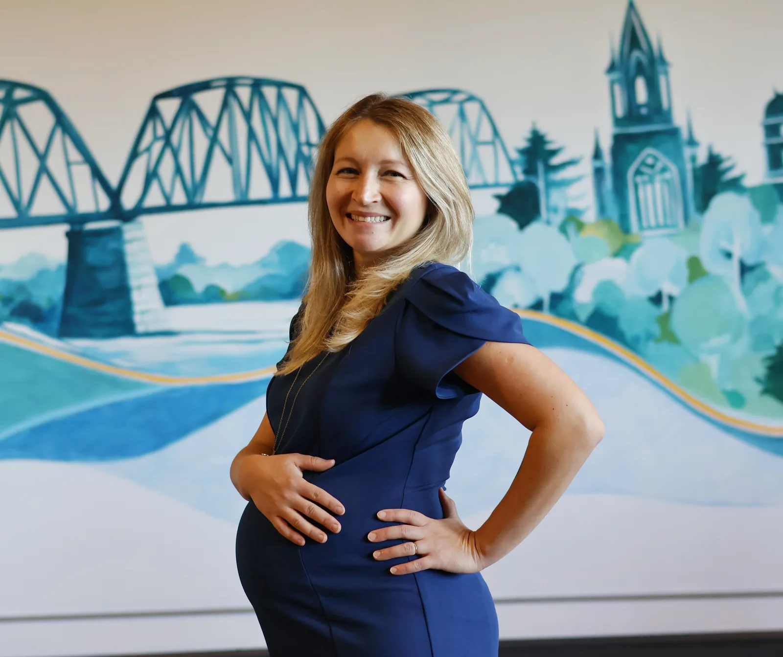 Corina, co-founder of Tidal Signal, smiling in front of the studio mural